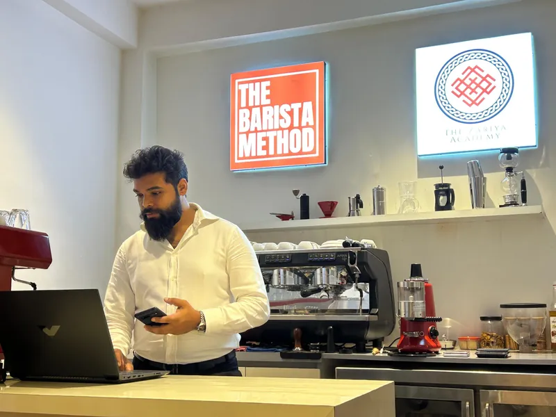 Shubham Jaiswal at the bar of The Zariya Academy lab, with The Barista Method and Zariya Academy signs behind him